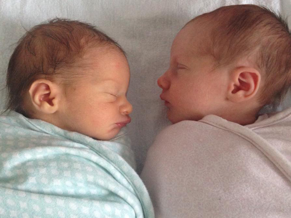 Newborn twins sleep next to each other in sleeping bags