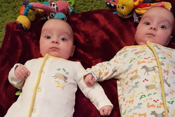 Twin babies lie on a mat