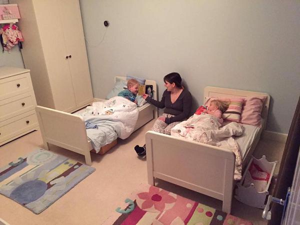 Twins in their new beds with their mum reading a story