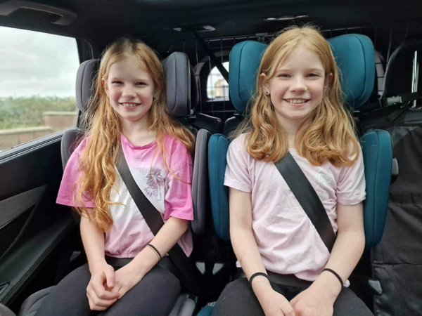 Twin girls smile whilst sitting in car seats