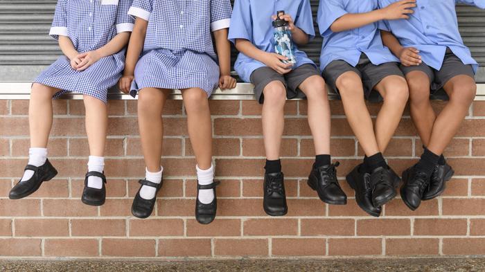 School children sitting on a wall
