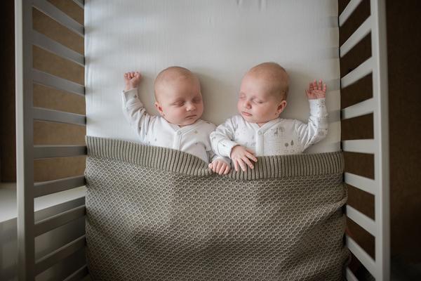 Young twins sleeping together in cot