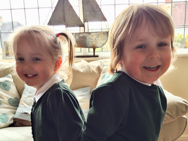 A boy and a girl turn to smile at the camera with their backs to each other