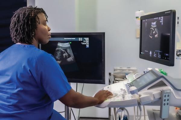 A female midwife looks at the screen on a sonography machine