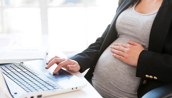 A pregnant women browsing the web on a laptop.