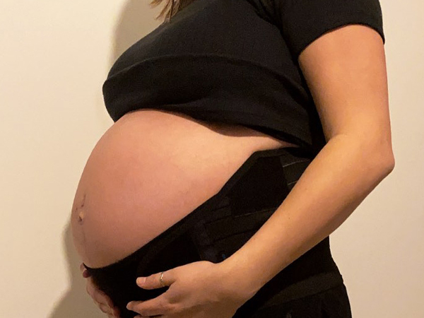 A cropped photo showing a woman holding her belly whilst pregnant