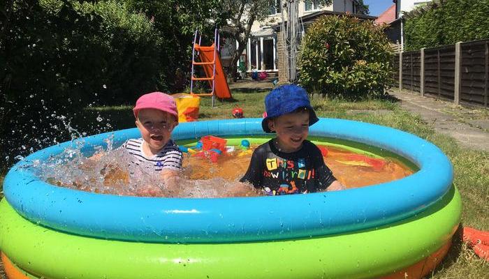 Twins playing in paddling pool