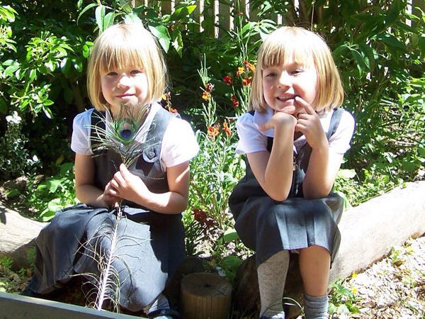 Two school age girls sit smiling at the camera